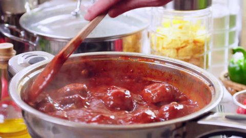 Cooking meatballs in tomato sauce to prepare spaghetti with meatballs. Slow motion