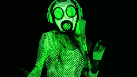 uv fluorescent female gogo dancer dances wearing a gasmask
