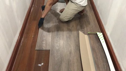 man put the vinyl laminate floor tile on the floor for renovate home. for home decoration design by interior. Wood Laminate setup.