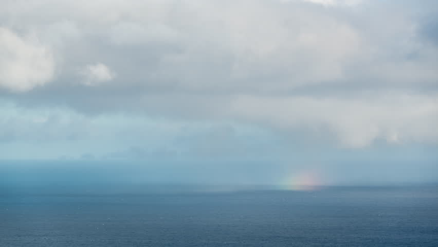Timelapse. Rainbow over Ocean with Moving Clouds