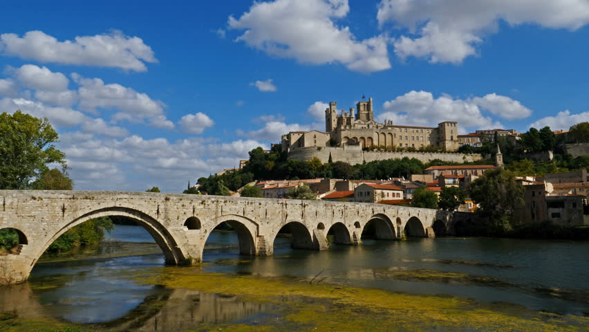 Beziers, Herault, Occitanie, France. In the foreground, the old bridge over crossing  the Orb river. In the background is the cathedral Saint Nazaire 