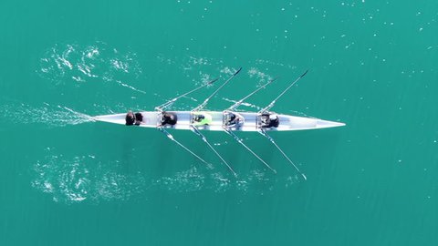 Aerial drone bird's eye view video of sport canoe operated by team of young women in emerald clear waters