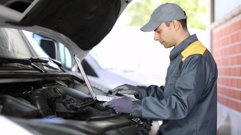 Mechanic using a laptop computer to check a truck engine