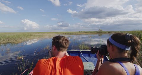 Everglades Airboat tour and alligator - tourists taking picture of alligators on ecotourism travel vacation in Everglades Florida. Airboat tours are a famous tourist activity in the Everglades.