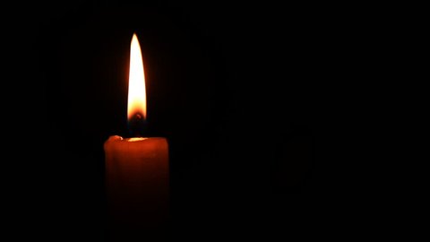 Burning candle on black background