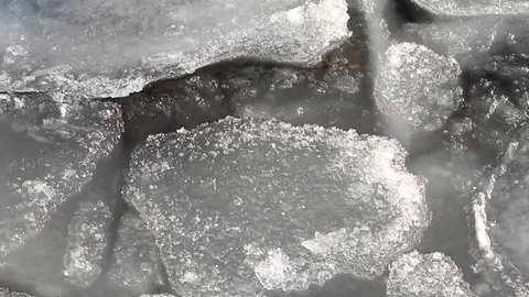 Pieces of transparent melting ice swing on the waves close-up. Lake Baikal in winter