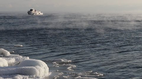 the ship sails on the lake Baikal floating from frost along the icy coast in January