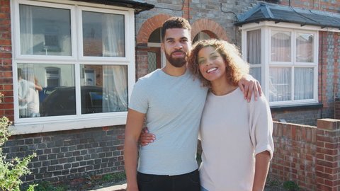 Portrait Of Young Couple Standing Outside New Home In Urban Street