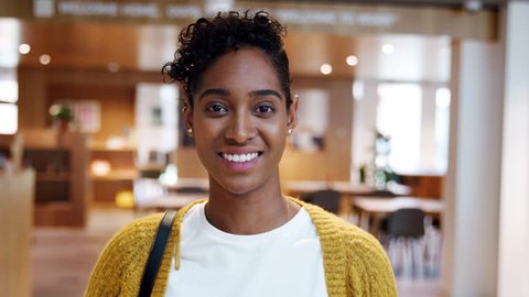 Young mixed race woman standing in a business lobby on her way out from work, looking to camera