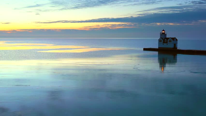 Iconic Lighthouse standing tall in frozen Lake Michigan harbor, Winter dawn.
