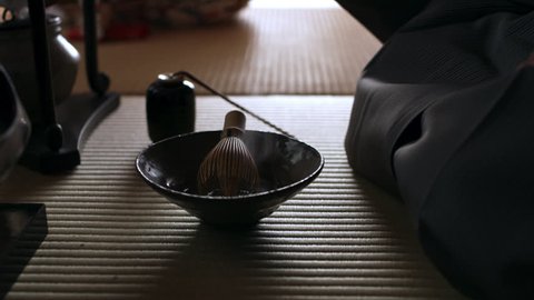Male tea master using a bamboo matcha tea whisk to whisk the powder with hot water in a bowl in a traditional Japanese home with soft day lighting. Close up shot on 4k RED camera.