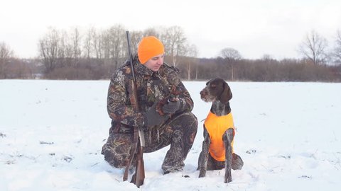 pleasant man is thanking his dog for help during hunting. rest, excellent weather for hunting