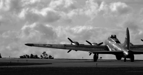 WWII B17 Flying Fortress airplane driving on tarmac towards runway - silhouetted in back and white