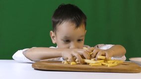 Little cute kids - the boy plays the cook. A little boy is chopping potatoes.