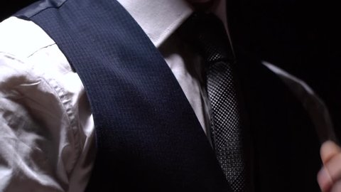 Businessman adjusting his tie while putting on his three piece suit