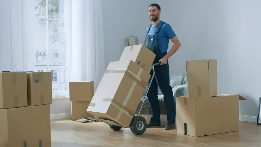 Professional Mover with Hand Truck Loads it With Cardboard Boxes and Helps People Move out and Relocate into the New House. Shot on 4K (UHD) Camera. Royalty-Free Stock Footage #1022013604