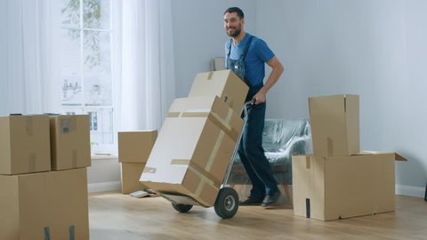 Professional Mover with Hand Truck Loads it With Cardboard Boxes and Helps People Move out and Relocate into the New House. Shot on 4K (UHD) Camera.