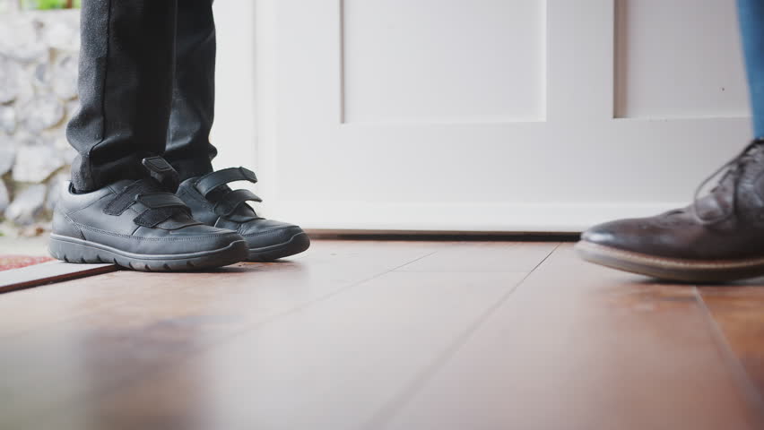 Close up of father wearing shirt and tie, brogue shoes and striped socks kneeling down on one knee to fasten the straps on his sons shoes before school, low section, close up of feet Royalty-Free Stock Footage #1022014042