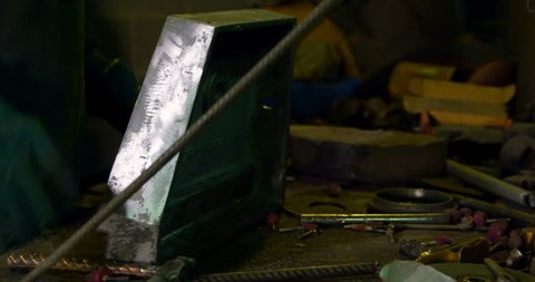 Side view of worker working in foundry workshop. Worker hammering metal in workshop 