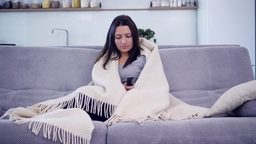 A woman is watching TV with a blanket 