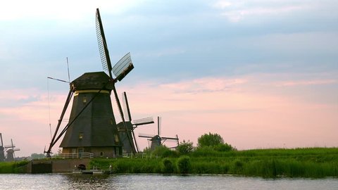 Spectacular view of row of old windmills and canal with reeds and ducks. Group of drainage system structures. Watertable control in agricultural land. Alblasserwaard polder, Knderdijk, Netherlands.