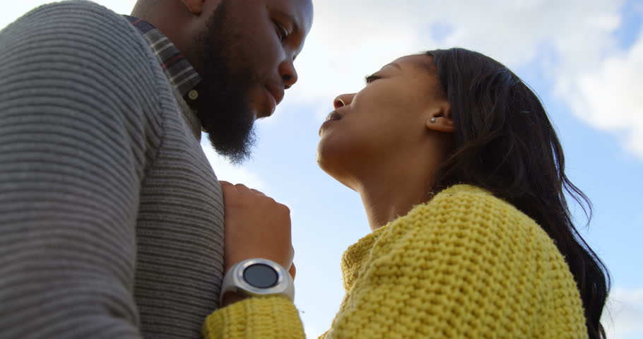 Romantic African-American couple kissing each other on a sunny day. Beautiful sky and cloud in the background 4k