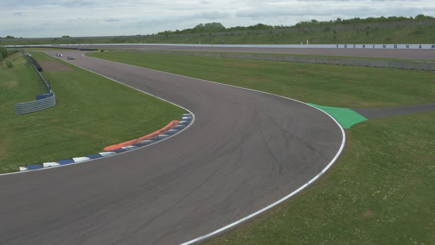 Two super cars driving around race track corner at speed