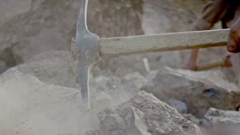 Miner or gold digger breaking rock by digging axe . Close up of pickaxe hitting rocks .  Shot on RED EPIC DRAGON Cinema Camera in slow motion.