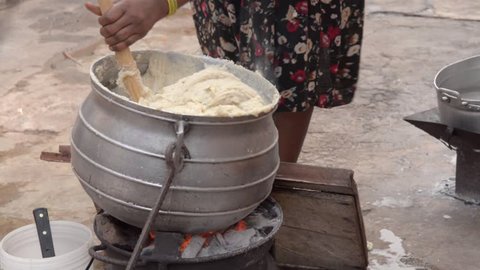 Accra, Ghana - January 7, 2019: African woman cooks Banku on a coal pot in the open in rural Ghana.