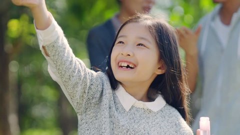 beautiful little asian girl blowing bubbles in park
