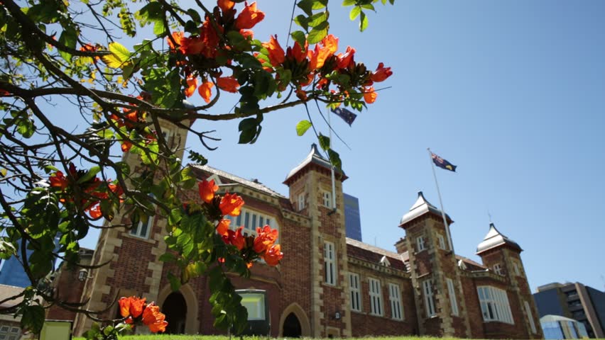 Bougainvillea in foreground with sunbeams in Government House Gardens, Perth city. Government House east front, the residence of Governor of Western Australia on background. Blue sky. Copy space.