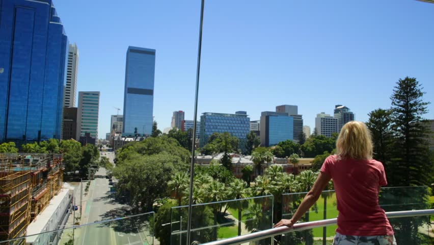 Blonde woman on the Bell Tower observation deck in Perth, Western Australia. Blue sky in a summer season. Elizabeth Quay activity. Caucasian tourist enjoys city views.