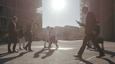 Office going pedestrians using their phones while commuting. Commuters being on their mobile phones walking to office.
