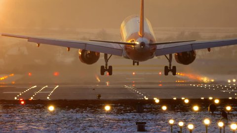 Commercial Jet Airplane Landing in airport runway at sunset in Winter. 