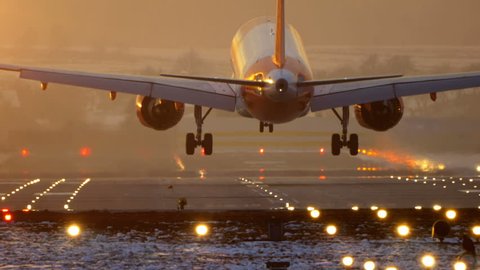 Commercial Jet Airplane Landing in airport runway at sunset in Winter. Slow pan.