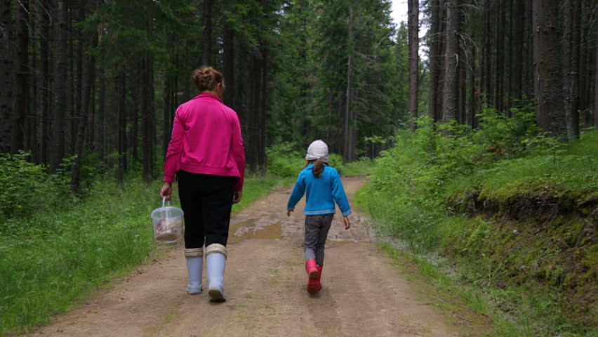Woman with little girl walking in forest