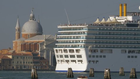 Large cruise ship sailing in Venice waterway and passing by Church of Santissimo Redentore, Italy