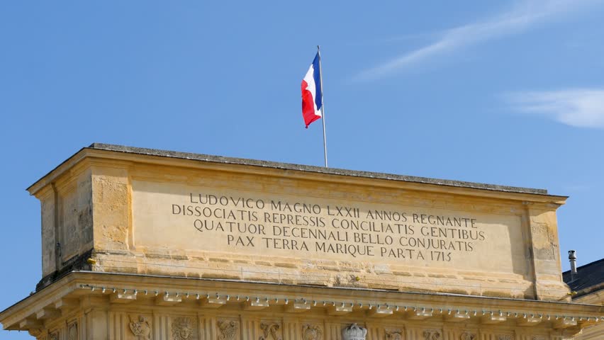 Flag in the wind over The Porte du Peyrou arch, a triumphal arch in Montpellier, in southern France. It is situated at the eastern end of the Jardin de Peyrou, a park near the center of the city. 