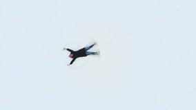 High quality 4K aerial video of woman making snow angel. 