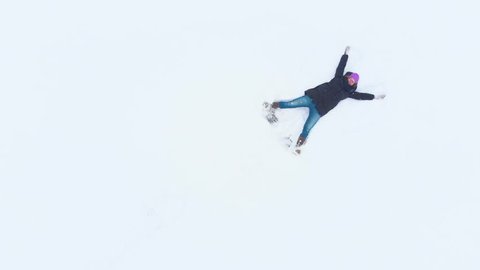 High quality 4K aerial video of woman making snow angel. 