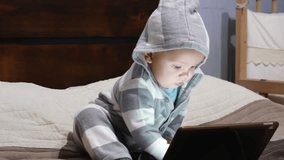Little boy in a striped suit uses a tablet. Early child development concept