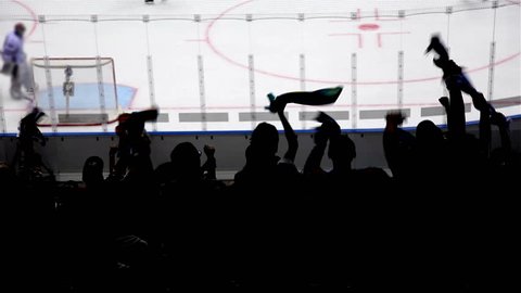 Silhouettes of fans rejoice at a goal in hockey.