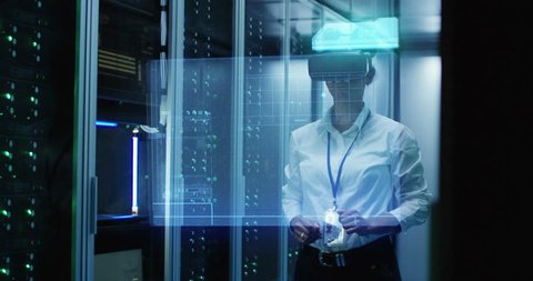 Medium shot of a black female technician in VR glasses using then turning off a virtual interface while working in a data center