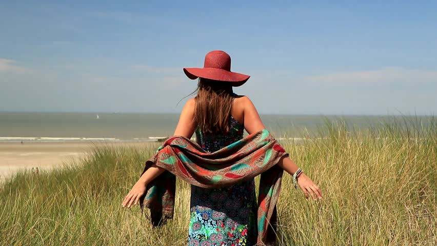 A young girl is walking in the long grass on a beautiful beach of the North Sea in Belgium.