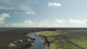 River flowing through the black plains of Southern Iceland, aerial drone footage