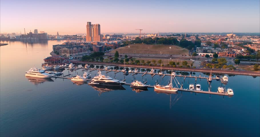 Aerial: Inner Harbor boats and city skyline in Baltimore, Maryland at sunrise. USA