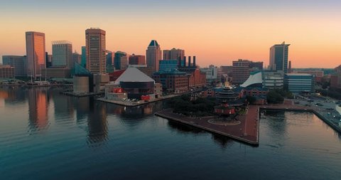 Aerial: Inner Harbor and boats and city skyline at sunrise in Baltimore, Maryland, USA.