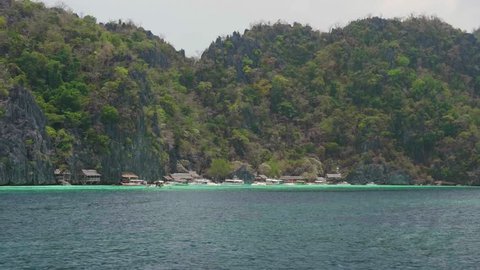 Small Houses On A Beach In A Tropical Archipelago With Permian Limestone Mountains, Steep Cliffs And Turquoise Water.