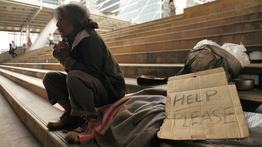 Homeless old man eating soup received from volunteers while sitting on stairs in the city