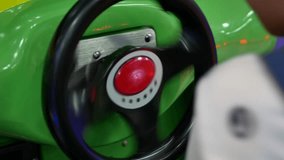 A steering wheel of an arcade car driving game being spun and turned by a little baby's hands
